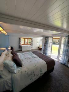 4 Palms Cottage Coromandel Town في كورومانديل تاون: غرفة نوم بسرير كبير في غرفة بها نوافذ