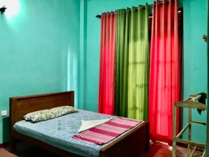 a bedroom with green and red curtains and a bed at Lucky's Homestay in Maho