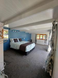 4 Palms Cottage Coromandel Town في كورومانديل تاون: غرفة نوم بسرير في غرفة زرقاء