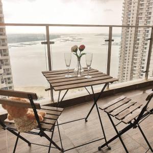 a table with two wine glasses and a flower on a balcony at seaview beach 4-13pax/CIQ 5mins/ johor bahru ambersite in Johor Bahru