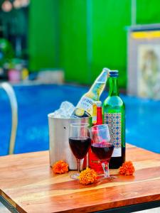 two glasses of wine and a bottle on a table at Hotel Grand Bhagwat, Udaipur in Udaipur