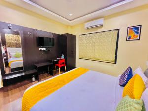 a bedroom with a bed and a desk and a television at Hotel Grand Bhagwat, Udaipur in Udaipur