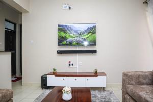 a living room with a couch and a tv on the wall at Kigoma Suites in Nyahururu