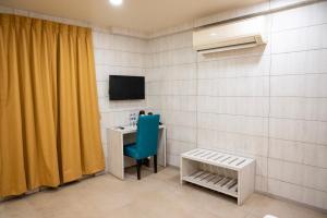 Cette chambre comprend un bureau, une télévision et une chaise. dans l'établissement The Opus Kolkata - A Boutique Hotel, à Kolkata