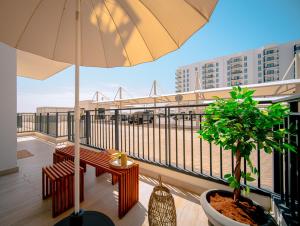 - un balcon avec un parasol, un banc et un arbre dans l'établissement One Bedroom Apartment By Voyage, à Abu Dhabi