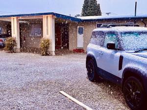 um carro coberto de neve estacionado em frente a uma casa em Manuka Crescent Motel em Wanaka