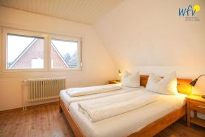 a large white bed in a room with a window at Ferienhaus Seehundje Ferienwohnung 21 in Borkum
