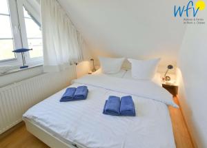 a bedroom with a bed with blue slippers on it at Luv und Lee Ferienwohnung Dornbusch in Juist