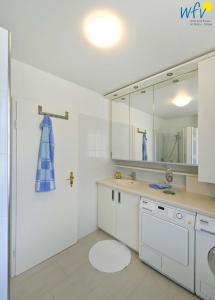 a white bathroom with a sink and a mirror at Juist Zauber - Haus 2 Ferienwohnung Helmers in Juist +25 photos