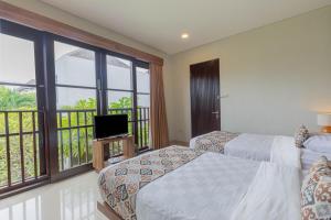 a bedroom with two beds and a balcony with a television at The BALIem Villa in Jimbaran