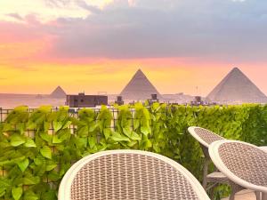 un patio con 2 sillas y pirámides en Lux pyramids View Inn en El Cairo
