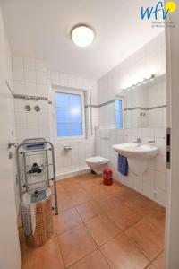 een badkamer met een wastafel, een toilet en een wastafel bij Luv und Lee Ferienwohnung Pilsum in Juist