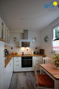 a kitchen with white cabinets and a wooden table with a tableablish at Haus Bode Ferienwohnung Bode in Borkum