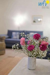 Luv und Lee Ferienwohnung Westerhever في جويست: مزهرية بيضاء مع زهور وردية في غرفة المعيشة