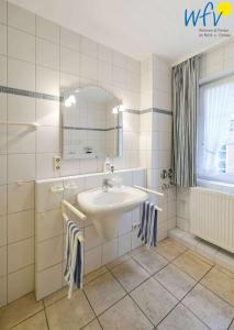a white bathroom with a sink and a mirror at Luv und Lee Ferienwohnung Westerhever in Juist