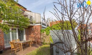 a patio with a table and chairs on a brick house at Juist Zauber - Haus 3 Ferienwohnung Strandaster in Juist
