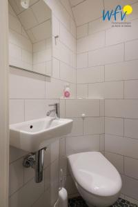 een witte badkamer met een wastafel en een toilet bij Juist Zauber - Haus 3 Ferienwohnung Ockjes Stuuv in Juist