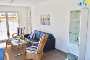 a living room with a black couch and chairs at Juist Zauber - Haus 2 Ferienwohnung Jansen in Juist
