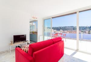 a red couch in a living room with large windows at Superb Rooftop Roquebrune Parking in Roquebrune-Cap-Martin