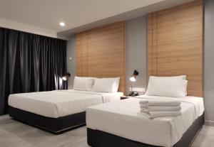 two beds in a hotel room with white sheets at Coral Bay Resort in Pangkor