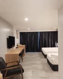 a hotel room with a bed and a desk and a bed and a television at Coral Bay Resort in Pangkor