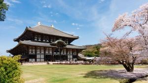 un gran edificio con un árbol florido delante de él en Ranjatai, en Nara