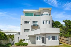 a white house with a blue sky at Seaside Symphony, Sleep and Wake to Ocean Waves in Wamberal