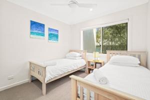 a bedroom with two beds and a window at Seaside Symphony, Sleep and Wake to Ocean Waves in Wamberal