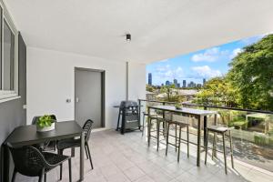a balcony with tables and chairs and a view of the city at Sleek 1-Bed With Rooftop Pool & Amazing City Views in Brisbane