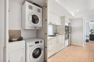 a kitchen with white cabinets and a washer and dryer at Sleek 1-Bed With Rooftop Pool & Amazing City Views in Brisbane