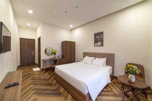 a bedroom with a large white bed and a desk at Tala Dalat Hotel in Da Lat