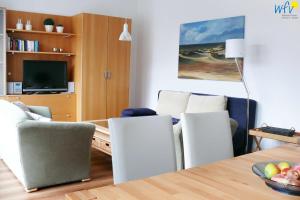 a living room with a table and chairs and a television at Haus Oberlin Ferienwohnung 8 in Borkum