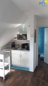 Il comprend une cuisine blanche équipée d'une cuisinière et d'un four micro-ondes. dans l'établissement Haus Hindenburgstr 13 Ferienwohnung Lüttje Land, à Borkum