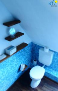 La salle de bains est pourvue de toilettes et d'un mur carrelé bleu. dans l'établissement Haus Hindenburgstr 13 Ferienwohnung Lüttje Land, à Borkum