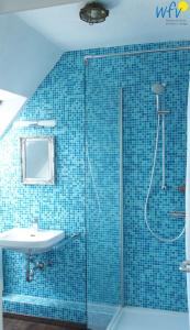 La salle de bains est pourvue de carrelage bleu, d'une douche et d'un lavabo. dans l'établissement Haus Hindenburgstr 13 Ferienwohnung Lüttje Land, à Borkum
