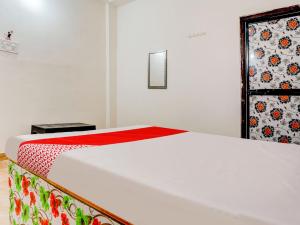 1 dormitorio con cama blanca y manta roja en OYO Flagship RJ Hotel en Nagpur