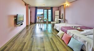 統営市にあるPaper island pensionのベッド2台とテレビが備わるホテルルームです。