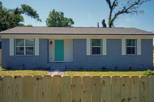 a house with a wooden fence in front of it at The Blue Pearl 6min to Downtown -Short Beach Drive in Pensacola
