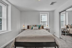 a bedroom with a large bed and two windows at Modern Renovated & Comfy East Germantown Adobe in Philadelphia