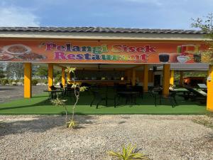 un restaurante con mesas y sillas frente a él en Capital O 90949 Pelangi Beach Resort Mersing en Mersing