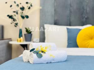 a stack of towels with flowers on a bed at 396I1 Blue Horizon Apartments Sholpan city in Almaty