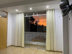 a living room with a large window with curtains at Hurin Hotel in Ica