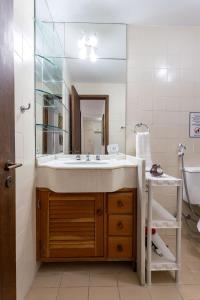 La salle de bains est pourvue d'un lavabo et d'un grand miroir. dans l'établissement 180m da PRAIA LEBLON, Piscina, Academia, Arrumação Diária etc., à Rio de Janeiro