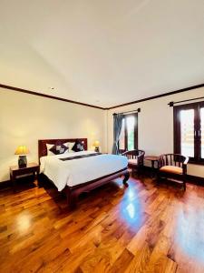 1 dormitorio con 1 cama grande y suelo de madera en Houngvilai Hotel en Luang Prabang