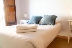 a white bed with blue pillows on top of it at Light House Sherry in Jerez de la Frontera