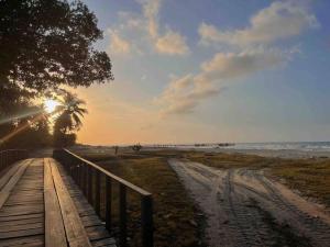 a wooden path to the beach with the sun setting at CASA LUNA ¡Piscina y Playa! in La Ceiba