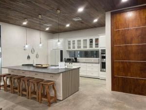 a kitchen with white cabinets and a large island with bar stools at CASA LUNA ¡Piscina y Playa! in La Ceiba