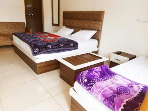 a hotel room with two beds with purple blankets at Hotel Lake View Paradise in Uttarkāshi