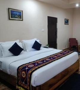 a bedroom with a large white bed with blue pillows at Hotel Silicon Residency Puri Excellent Service Awarded - Parking & Lift facilities in Puri