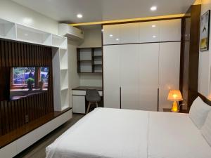 1 dormitorio con 1 cama blanca y TV en BaoTran Apartment & hotel, en Ðông Khê